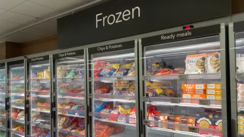 Photo of glass freezer doors in supermarket containing lots of colourful products