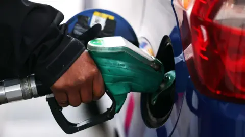 EPA An anonymous hand holds onto a pump which is going into his blue car.