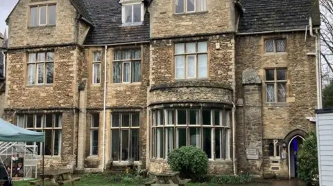 Shariqua Ahmed/BBC Exterior of The Garden House- a large stone building with glass windows.