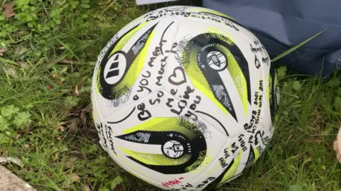 A ball is signed in tributes to Amelia Aplin.