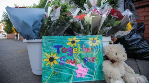 A sign which reads 'Together for Southport' next to a teddy 