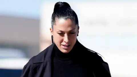 Reuters Jenni Hermoso looks down outside the court. She has long black hair slicked into a high pony tail and wears a double breasted black coat and black turtle neck