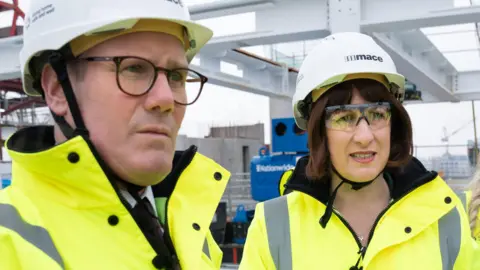 PA Prime Minister Sir Keir Starmer and Chancellor Rachel Reeves wear high visibility jackets and hard hats