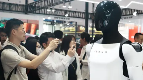 Future Publishing via Getty Images People snap pictures of Tesla's Optimus humanoid prototype at an exhibition in China.