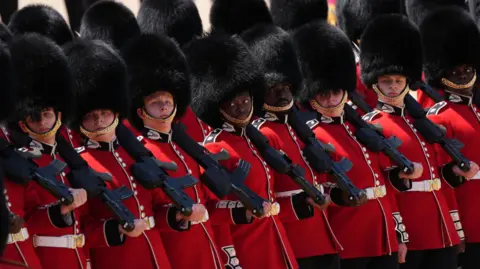 PA Media Scots Guards line up in uniform holding rifles in one hand, resting on their shoulder