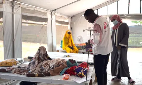 Medics look at a female patient with a drip at a health centre in Sudan