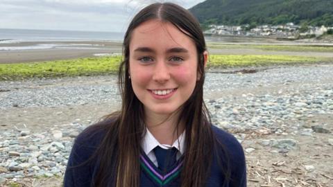 a girl in Shimna College uniform, photographed on the beach at Newcastle