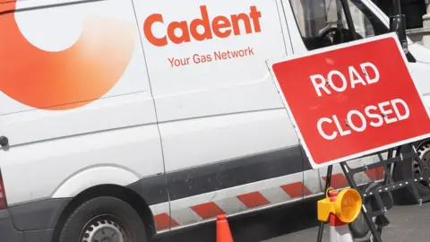 A white Cadent van parked behind a red sign that says "road closed" in white font.