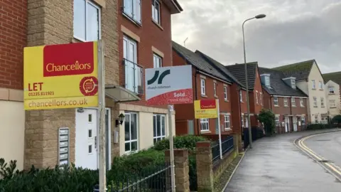 A row of houses on a new build housing estate. There are signs saying "sold" and "to let".