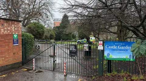 Leicester Media Gates to a city park, with a sign saying Castle Gardens on the fence. Visible behind is a police van and tape