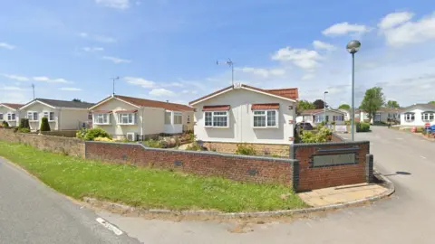 Google Part of Lillybrook Estate which shows white and cream homes behind a brick wall