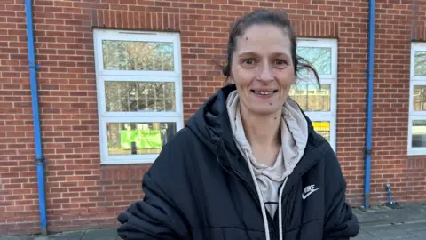 Lisa Bailey stands on Southwick green which is metres away from Southwick Community centre. She has tied-back black hair.