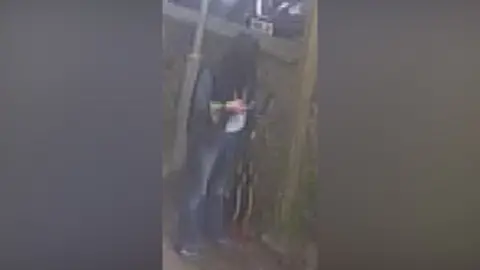Devon and Cornwall Police Blurry CCTV footage of Holly Collinson looking down at her hand.
