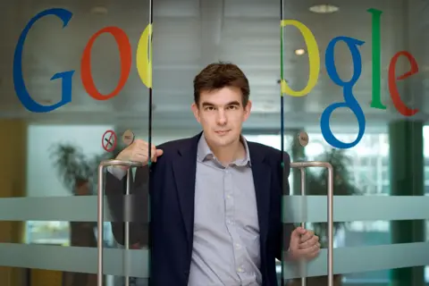 Shutterstock Matt Brittin in a suit in 2009 walking through a pair of glass doors with a large Google logo across them