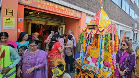 People are standing outside a Hindu temple in Swindon.
