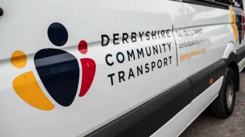 A white people carrier van with a Derbyshire Community Transport logo on the side of the vehicle