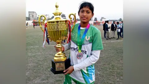 Supplied A young woman wearing a medal holds up a trophy