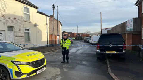 BBC Image of a police officer standing in front of a cordon