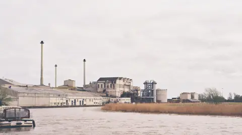 Owen Sennitt/BBC Looking at the Cantley sugar factory from upstream, with its buildings, the river and a boat in view