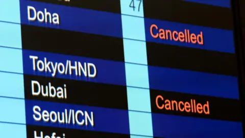 Cancelled flights to Dubai and Doha shown on flight information display at Hong Kong International Airport