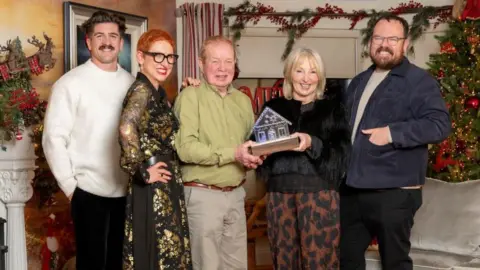 Kirsty Anderson The judges and homeowners standing in front of festive decorations smiling at the camera and holding the trophy. L-R: Danny Campbell, Anna Campbell-Jones, Gary, Ellenor, Banjo Beale.