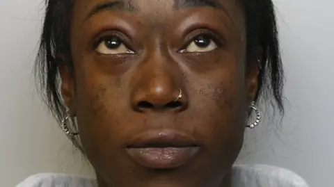 Avon and Somerset Police A woman facing a camera, looking up, wearing two silver hoop earrings.