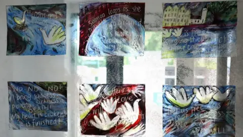 Forest of Dean District Council A series of glass panels which have been created by artists. There are birds and swans drawn on water which are covered in white writing.