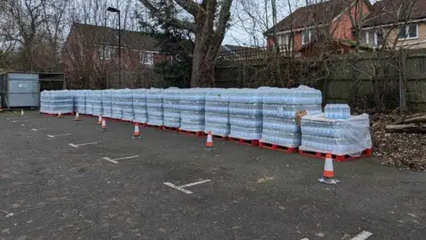 Harrison Galliven Bulk shipments of bottled waters in a car park.