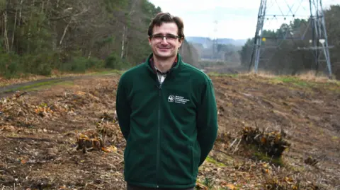 Matthew Stanton from the Berks, Bucks and Oxon Wildlife Trust smiling for the camera. It is a cloudy day.