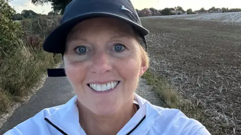 Maggie's A selfie of a woman next to a field wearing a cap