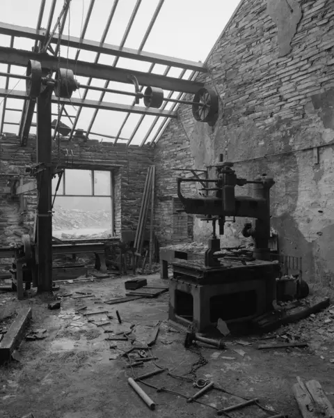 Kyle McDougall Kyle's black and white photograph of abandoned machinery in a partially ruined stone building with no roof