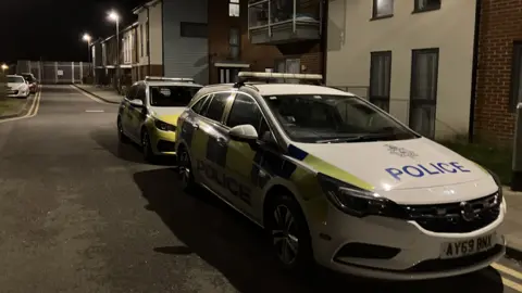 Two police cars parked up at night outside a block of flats