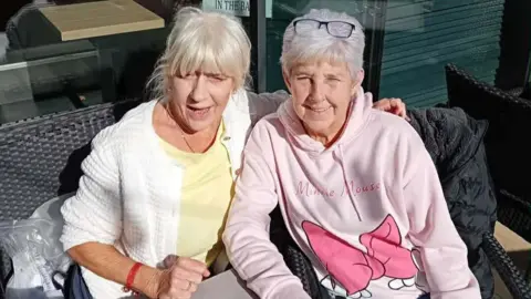 Marie Casey Two women with grey hair sitting posing for picture.