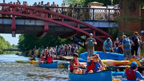 Leicester City Council An image of people using boats on the River Soar in Leicester, while spectators look on from a bridge.