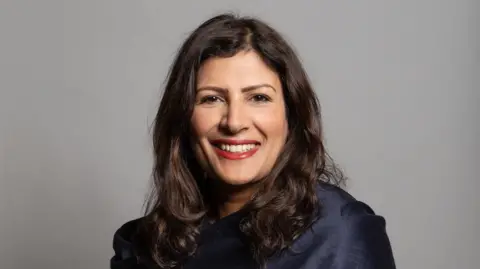 UK Parliament Preet Gill wearing a blue scarf with a gray background