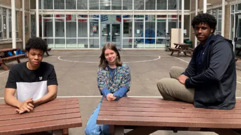 BBC Zach, Jess, Abdirisaq sat on benches outside their college