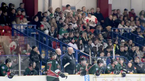 Rows of Bison ice hockey fans watch on as their team play a game on the ice in front of them