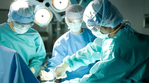 Getty Images Surgeons operating using surgical equipment.