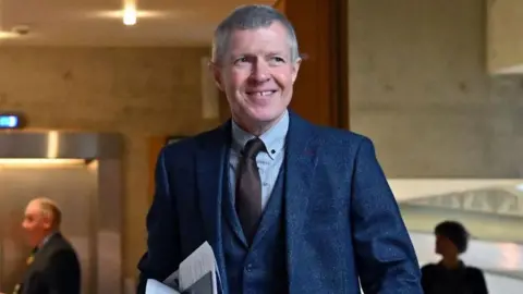 Getty Images Former Lib Dem leader Willie Rennie at Holyrood. He is wearing a dark blue three-piece suit, a brown tie and a light blue shirt