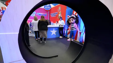 Getty Image Toy Fair with a display clusted around the booth with a giant doll and a giant doll with cat's ear