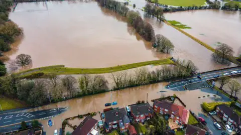 Alderley Aerial Photography An aerial view of houses and fields partially submerged in brown flood-water