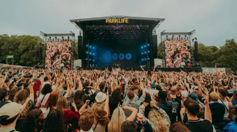 Music fans with their hands in the air in front of a stage at Parklife at this year's festival