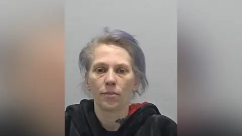 Bedfordshire Police The head and shoulders of a woman with swept back grey hair wearing a black top.