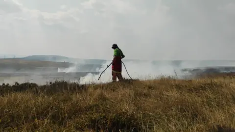 Peak District National Park Authority A silhouette of a person spraying a hotspot on the moors