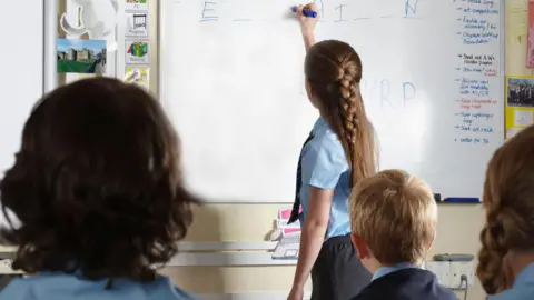 A pupil with her back to the class, drawing on a whiteboard.