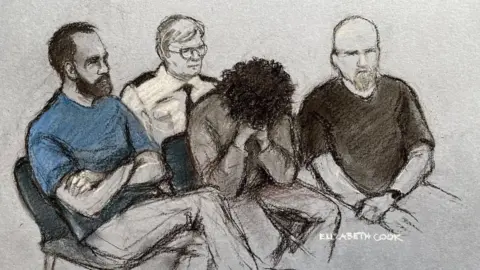 Elizabeth Cook A court sketch of Axel Muganwa Rudakubana wearing a grey sweatshirt and covering his face, surrounding by court officials sitting down