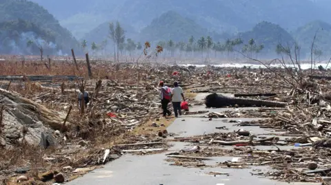 Getty Images Two Indonesian refugees walk down a road covered with debris leftover from the tsunami disaster, as they return to look for their homes in the west coast town of Leupung.