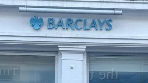 A close up of the Barclays logo above two windows. it it light blue and features a logo in the shape of an eagle.