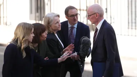PA Media Four journalists hold out microphones in front of minister Pat McFadden
