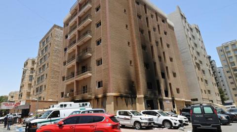 Vehicles are parked next to a building damaged following a deadly fire, in Mangaf, southern Kuwait, June 12, 2024